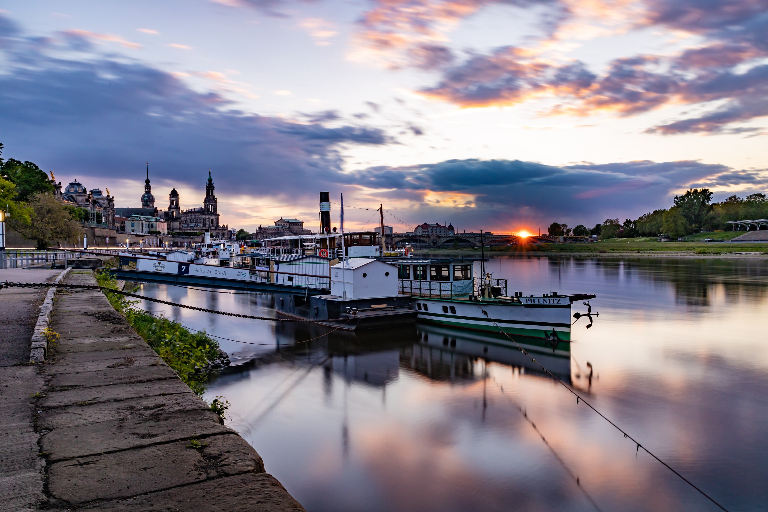 Dresden Dampfer Altstadt Elbe Sonnenuntergang Ein Dampfer liegt am Ufer der Elbe an. Im Hintergrund wird die Altstadt von Dresden in rosafarbenes Licht getaucht durch den Sonnenuntergang.