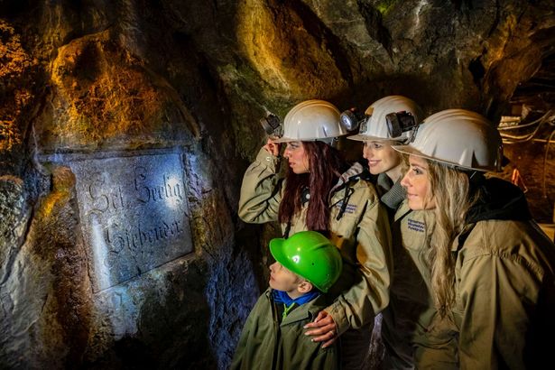 Eine Gruppe macht einen Bergmannsschmaus im Silberbergwerk Reiche Zeche in Freiberg. Sie haben eine Platte auf dem Tisch und stoßen miteinander an.