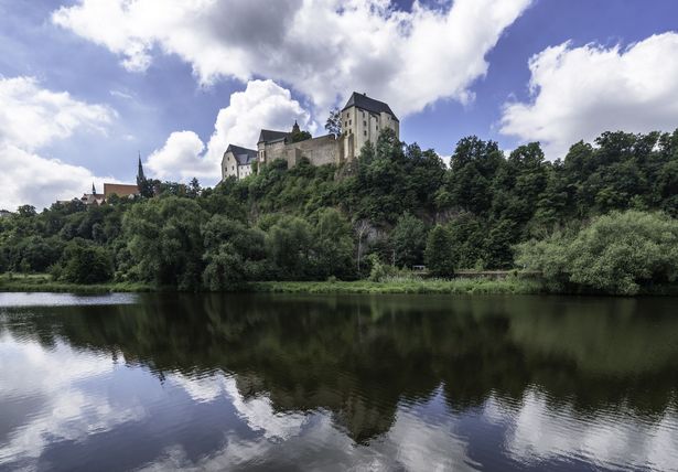 Blick vom Fluss auf eine Anhöhe mit Burg