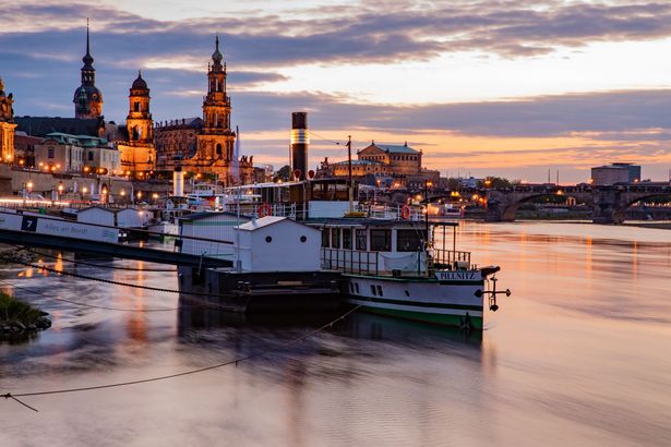Dampfer auf der Elbe mit beleuchteter Altstadt im Sonnenuntergang