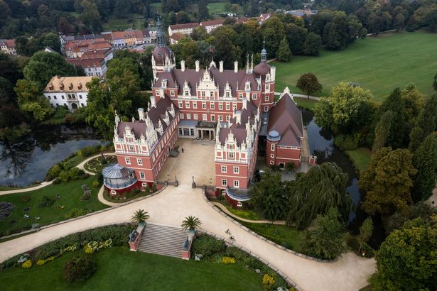 Luftaufnahme des Schlosses im Park Muskau mit seiner dunkelroten Fassade.