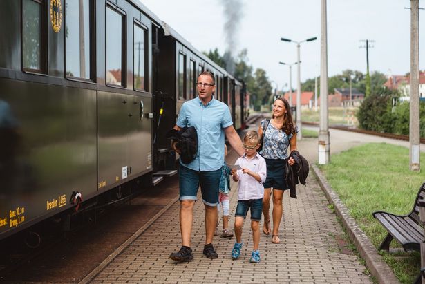 Familie läuft neben Schmalspurbahn